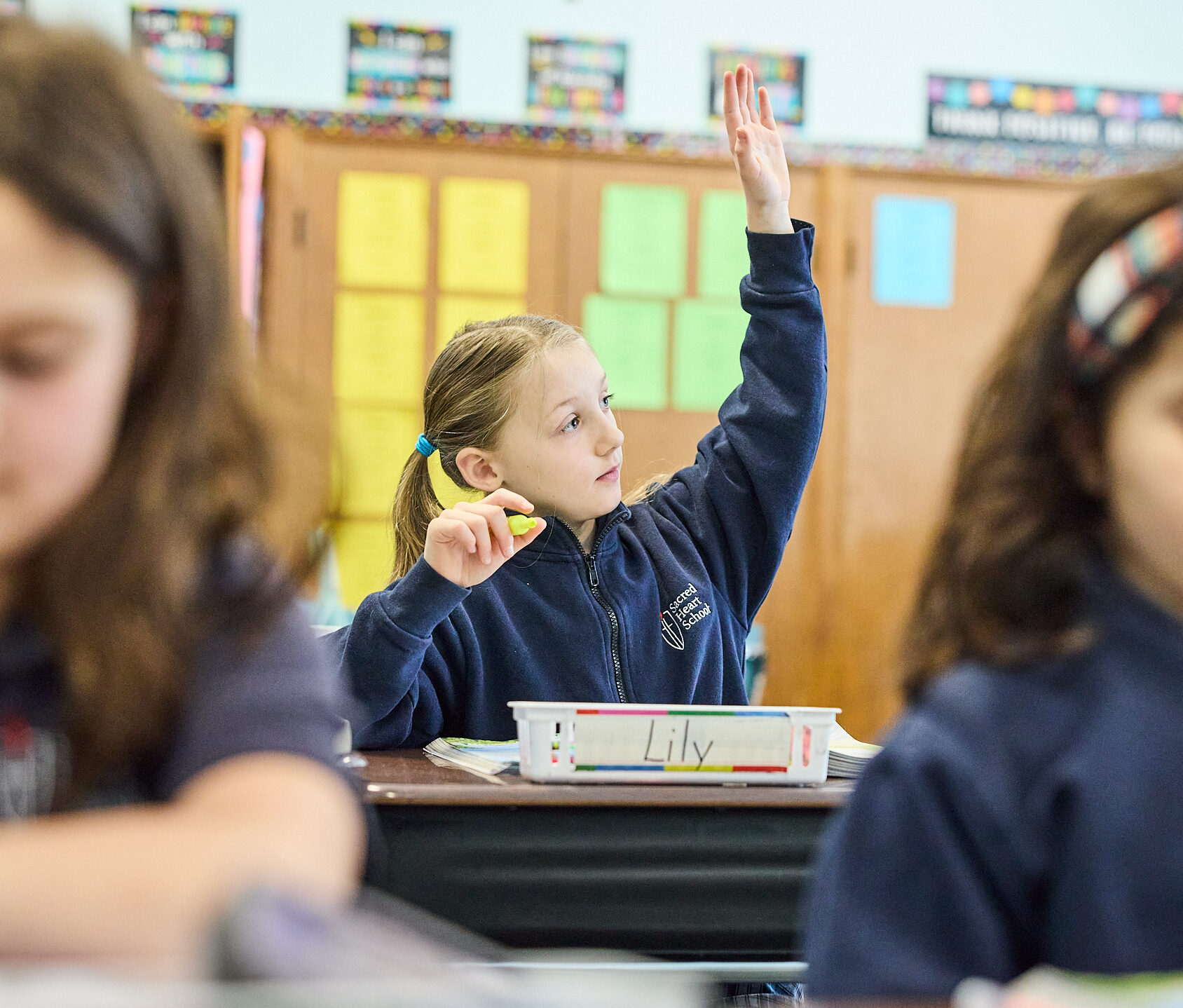 Sacred Heart student in class raising hand